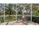 Secluded patio area under screened enclosure, offering serene seating amidst verdant landscaping and tranquil water views at 7319 Westminster Ct, University Park, FL 34201
