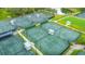 Aerial view of multiple tennis courts, complete with shaded seating areas and well-maintained green surfaces at 7319 Westminster Ct, University Park, FL 34201
