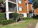 Exterior view showcasing a charming orange building with enclosed balcony and well-maintained landscaping at 8325 38Th Street E Cir # 101, Sarasota, FL 34243