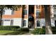 Exterior view of building with orange paint, stone accents, black railings and lush landscaping at 8325 38Th Street E Cir # 101, Sarasota, FL 34243
