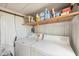 Functional laundry area with a washer, dryer, and overhead shelving for organized storage at 10315 Cortez W Rd # 24H, Bradenton, FL 34210