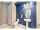 A half bath features an oval mirror, a pedestal sink, and contrasting wall colors at 11092 58Th Street Cir E, Parrish, FL 34219