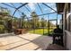 A screened patio area features a grill, dining table, and an inviting backyard view at 11092 58Th Street Cir E, Parrish, FL 34219