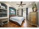 Well-lit bedroom with hardwood floors, TV, shelves, and a comfortable queen-sized bed at 12224 Garden Lake Cir, Odessa, FL 33556