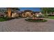 Stately home featuring a circular driveway, water fountain and meticulously landscaped garden at twilight at 12224 Garden Lake Cir, Odessa, FL 33556
