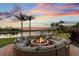 A custom fire pit with plush seating and a lake view, perfect for cozy outdoor gatherings at sunset at 12224 Garden Lake Cir, Odessa, FL 33556