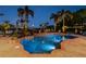 A tranquil pool area illuminated at dusk with lush landscaping and serene lake views create a peaceful ambiance at 12224 Garden Lake Cir, Odessa, FL 33556