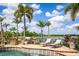 Inviting pool area with sun loungers, an outdoor kitchen, lush landscaping, and a lake view at 12224 Garden Lake Cir, Odessa, FL 33556