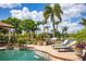 Beautiful outdoor pool area with palm trees, lounge chairs, grill, and a lake view at 12224 Garden Lake Cir, Odessa, FL 33556