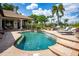 Lush backyard featuring a large in-ground pool with fountains, an outdoor kitchen, lounge area, and tropical landscaping at 12224 Garden Lake Cir, Odessa, FL 33556