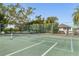 Outdoor tennis court featuring a green playing surface, net, and surrounding trees at 1235 Dockside Place # 108, Sarasota, FL 34242