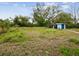 A large backyard featuring an outbuilding is surrounded by overgrown foliage at 13241 Miami St, Hudson, FL 34667