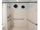 Modern bathroom featuring a walk-in shower, grab bars, decorative wall art and neutral colored tiles at 13241 Miami St, Hudson, FL 34667