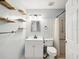 Bright bathroom featuring floating shelves, updated vanity with storage, and walk-in shower with shower curtain at 13241 Miami St, Hudson, FL 34667