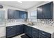 Bright kitchen featuring blue cabinets, stainless steel sink, and decorative backsplash at 13241 Miami St, Hudson, FL 34667