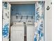 Laundry room features a washer and dryer, shelf, and privacy curtain with floral design at 13241 Miami St, Hudson, FL 34667