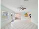 Open living room with light walls, tile floors, ceiling fan, and glass doors to the outdoors at 13241 Miami St, Hudson, FL 34667