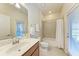 Bright bathroom featuring tile flooring, large mirror, wood cabinets, and shower with curtain, providing a clean and functional space at 135 Sweet Tree St, Bradenton, FL 34212
