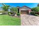 Charming single-Gathering home featuring a brick-paved driveway, lush landscaping, and an attached two-car garage at 135 Sweet Tree St, Bradenton, FL 34212