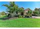 Charming single-Gathering home featuring lush landscaping, tropical palm trees, and an attached two-car garage at 135 Sweet Tree St, Bradenton, FL 34212