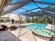 Inviting screened-in pool area with a jacuzzi, sun loungers, and an outdoor kitchen at 142 Dory Ln, Osprey, FL 34229