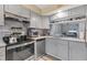 Modern kitchen with gray cabinets, stainless steel appliances, granite countertops, and tile flooring at 1533 42Nd Avenue E Dr # 48, Ellenton, FL 34222