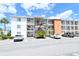 Exterior shot of a three-story condominium building with parking and lush palm trees under a beautiful blue sky at 2227 Sunset Dr # E22, Bradenton, FL 34207