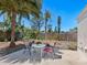 Backyard patio with table and chairs under a lush palm tree, bordered by a wooden fence at 2720 Herwald St, Sarasota, FL 34231