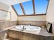 Bright bathroom featuring a soaking tub beneath a skylight and neutral earth toned tiles at 2720 Herwald St, Sarasota, FL 34231