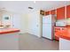 Retro kitchen featuring orange countertops and cabinets, with white appliances and tile flooring at 2720 Herwald St, Sarasota, FL 34231