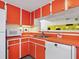 Cozy kitchen with orange cabinets, white appliances, stainless steel sink, and neutral tiling at 2720 Herwald St, Sarasota, FL 34231