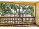 Screened condo balcony with wood railing offering views of mature trees at 3403 Clark Rd # 203, Sarasota, FL 34231