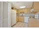 Well-lit kitchen featuring wooden cabinets, white appliances, and easy access to the storage area at 3403 Clark Rd # 203, Sarasota, FL 34231