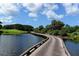Scenic wooden bridge over water leading to golf course and lush greenery under a bright, partly cloudy sky at 3621 North Point Rd # 603, Osprey, FL 34229