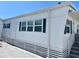 Side view of a well-maintained single-story home with white siding, black shutters, and manicured landscaping at 3710 Gulf Of Mexico Dr # E22, Longboat Key, FL 34228