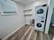 Laundry room with stacked washer and dryer, wood-style floors and storage shelving at 3710 Gulf Of Mexico Dr # E22, Longboat Key, FL 34228
