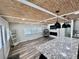 A living room with a fireplace, stylish egg chair, and wood-paneled ceiling seamlessly connects to the kitchen at 3710 Gulf Of Mexico Dr # E22, Longboat Key, FL 34228