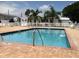 Community pool features crystal blue water and brick-laid patio with white lawn furniture at 3710 Gulf Of Mexico Dr # E22, Longboat Key, FL 34228