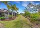 Expansive grassy backyard with view of the screened-in pool area and tropical landscaping at 3921 Waypoint Ave, Osprey, FL 34229