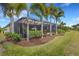 Wide backyard view highlighting the screened-in pool area surrounded by manicured landscaping and palm trees at 3921 Waypoint Ave, Osprey, FL 34229