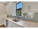 Modern kitchen featuring white cabinets, stainless steel sink, and gray backsplash at 3921 Waypoint Ave, Osprey, FL 34229