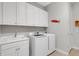 Well-lit laundry room featuring modern washer/dryer, ample storage, and a utility sink at 3921 Waypoint Ave, Osprey, FL 34229