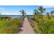 Picturesque path to the water, featuring lush greenery, flowers, and palm trees, leading to stunning water views at 3921 Waypoint Ave, Osprey, FL 34229
