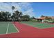 Community tennis courts with green and red surface, surrounded by mature trees at 3954 Wilshire Cir # 165, Sarasota, FL 34238