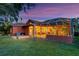A screened-in lanai extends from this beautiful home, overlooking the well-manicured lawn at dusk at 4926 Sabal Lake Cir, Sarasota, FL 34238