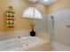 Bathroom featuring a soaking tub and glass enclosed shower, complemented by warm paint and tile at 4926 Sabal Lake Cir, Sarasota, FL 34238
