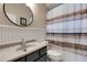 Well-lit bathroom with a round mirror over a granite sink, a toilet, and a striped shower curtain at 4926 Sabal Lake Cir, Sarasota, FL 34238