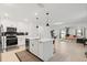 Modern kitchen featuring white cabinets, an island with a sink, and stainless steel appliances, with an open view to the living room at 5317 Patano Loop, Palmetto, FL 34221