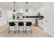 White cabinets and black backsplash highlight a well-equipped kitchen with an island and modern pendant lighting at 5317 Patano Loop, Palmetto, FL 34221