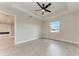 Bedroom showing gray wood floor and tray ceiling with black ceiling fan at 5322 Syracuse Rd, Venice, FL 34293